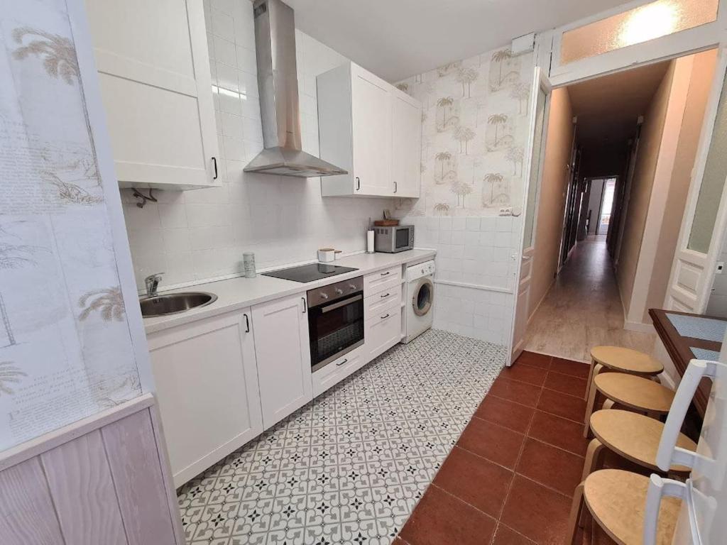 Elle comprend une petite cuisine avec des placards blancs et un évier. dans l'établissement 122A - Emblemática vivienda en Playa San Lorenzo, à Gijón