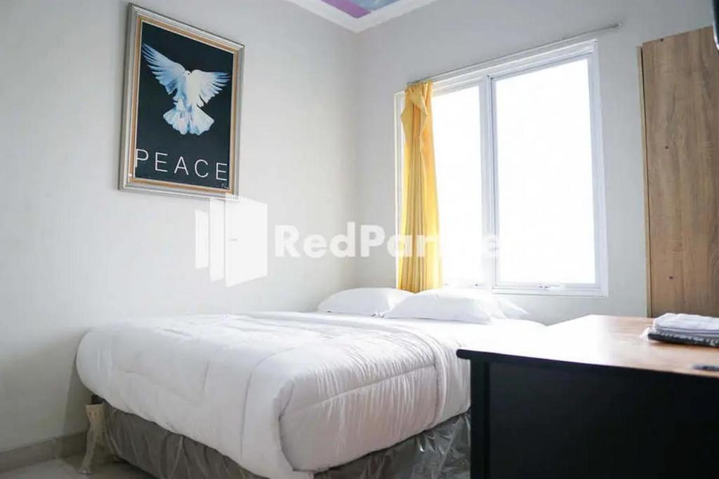 a white bedroom with a large bed and a window at Karawaci Victory Homestay Mitra RedDoorz in Tangerang