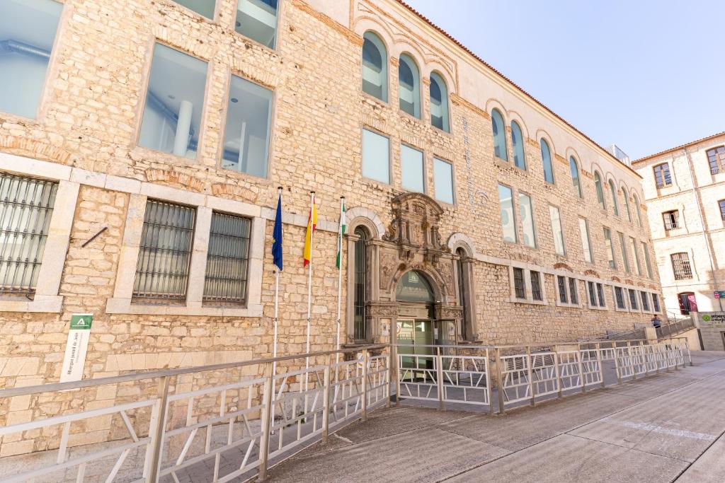 un bâtiment en briques avec deux drapeaux devant lui dans l'établissement Albergue Inturjoven Jaen, à Jaén