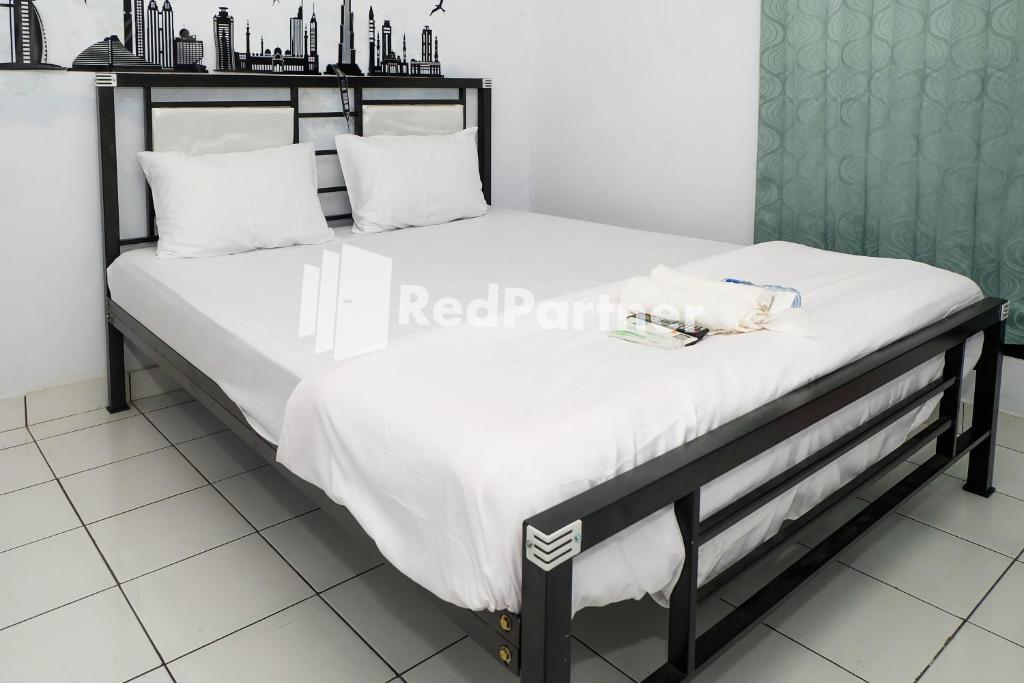 Una cama con sábanas blancas y almohadas blancas. en Ninja Room Pasteur Mitra RedDoorz, en Bandung