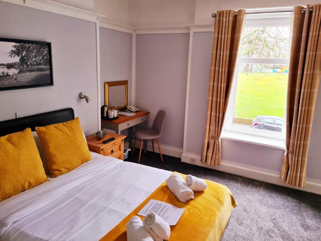 a bedroom with a bed and a desk and a window at The Market Inn Hotel in Castle Douglas