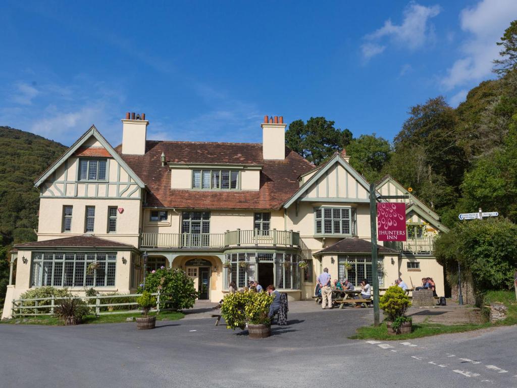 una casa grande con gente sentada fuera de ella en The Hunters Inn, en Martinhoe