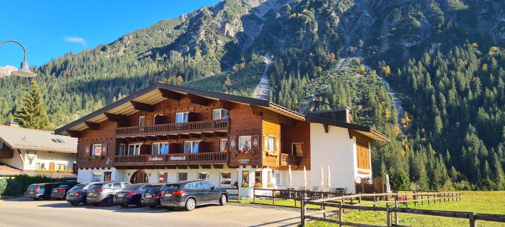 a large building with cars parked in front of a mountain at Landhaus Almrausch in Mittelberg