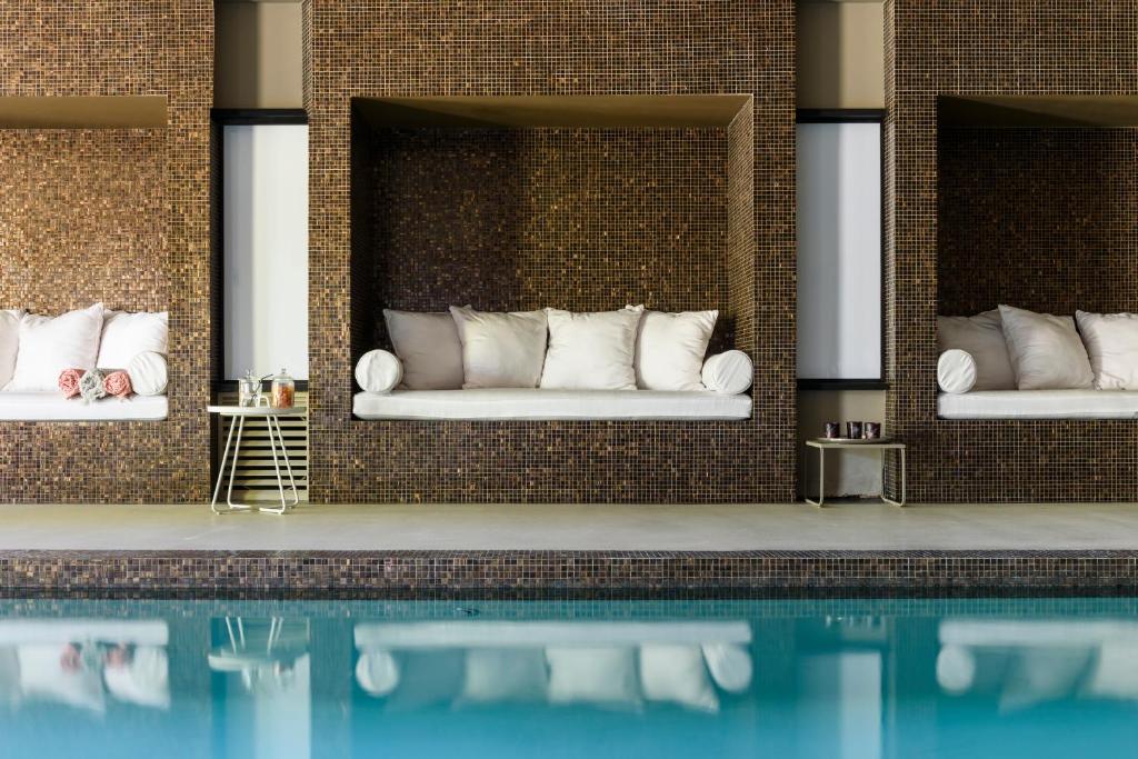 a swimming pool with two beds in a brick wall at Les Lodges Sainte-Victoire Hotel & Spa in Aix-en-Provence