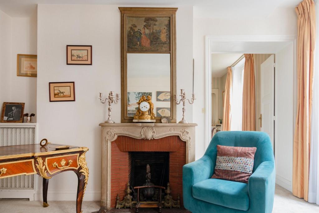 un salon avec une chaise bleue et une cheminée dans l'établissement Saint-Germain Prestige Residence, à Paris