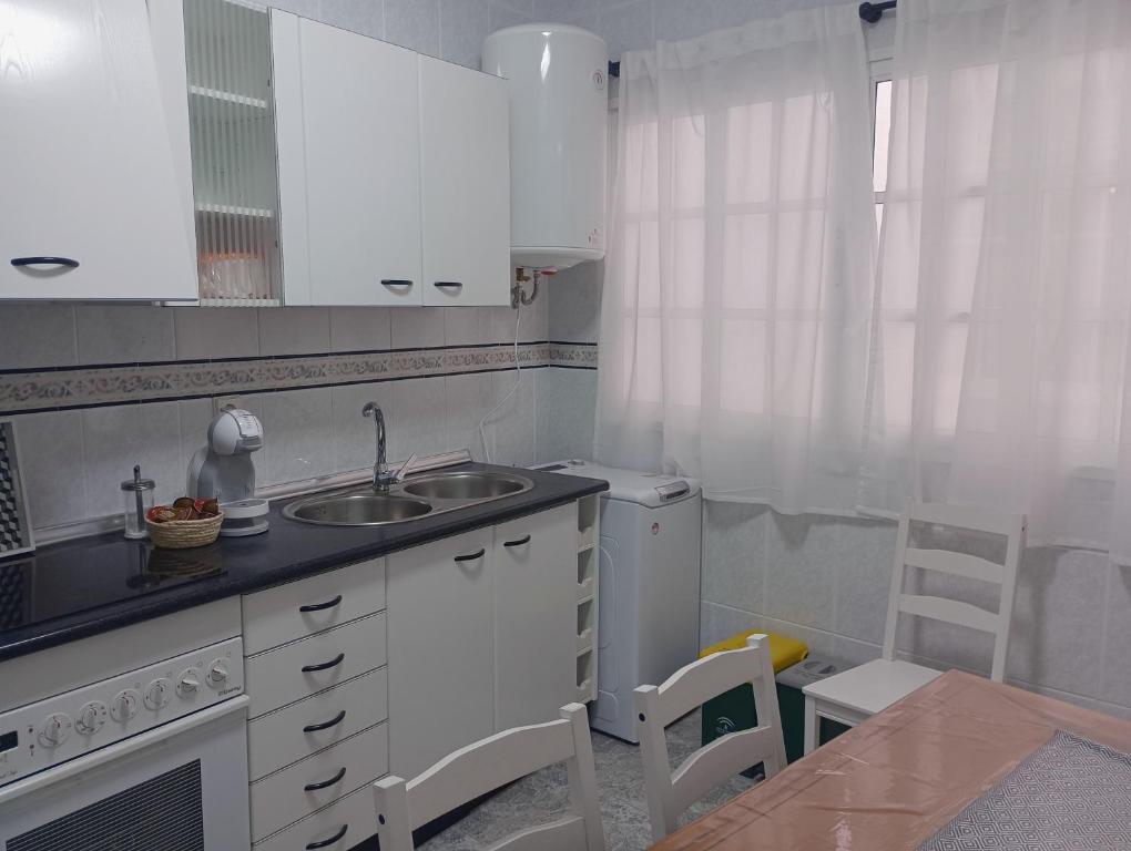 eine Küche mit weißen Schränken, einer Spüle und einem Tisch in der Unterkunft VACATIONAL HOMES South Organic in Málaga