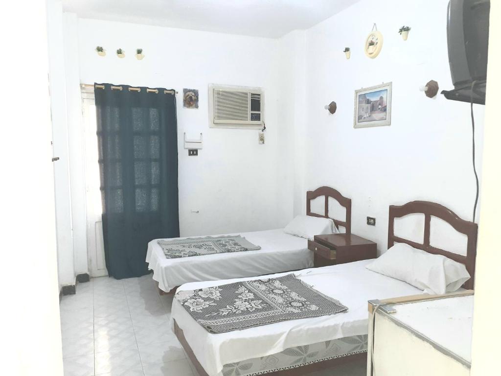 two beds in a room with white walls at Four Seasons Hotel in Hurghada