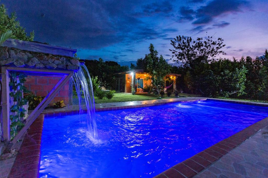 a pool with a waterfall in a backyard at night at LAS ORQUIDEAS in Rozo