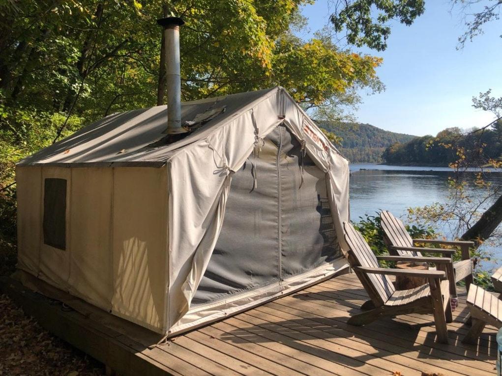 a tent sitting on a deck next to a chair at Tentrr Signature Site - River's Edge Sunset in Pond Eddy