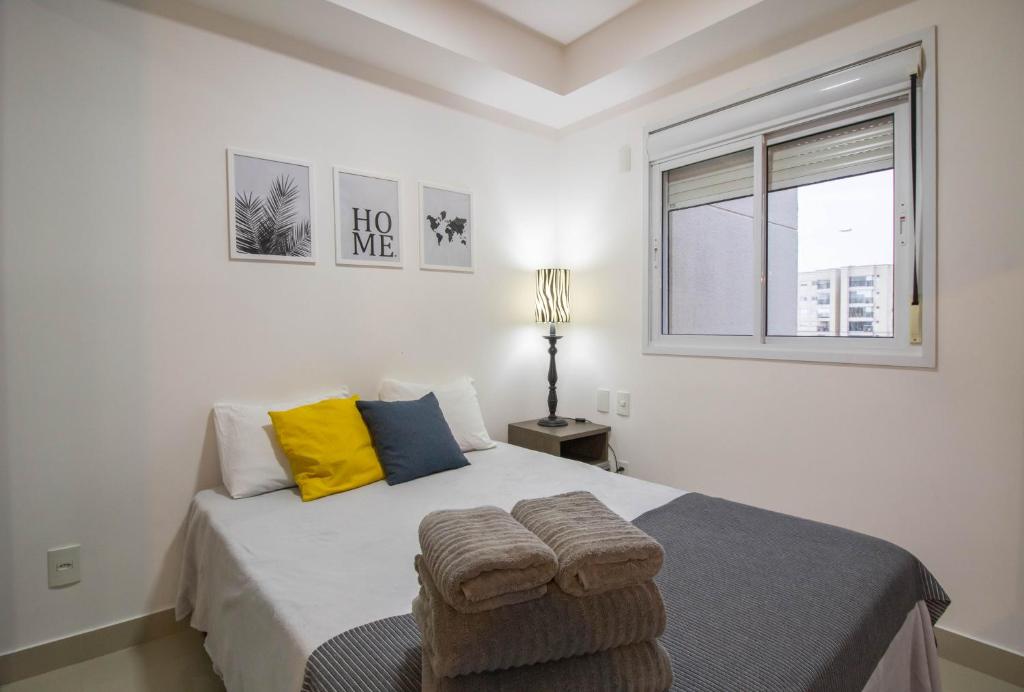 a white bedroom with a large bed with a window at Bright Studio - GRU in Guarulhos