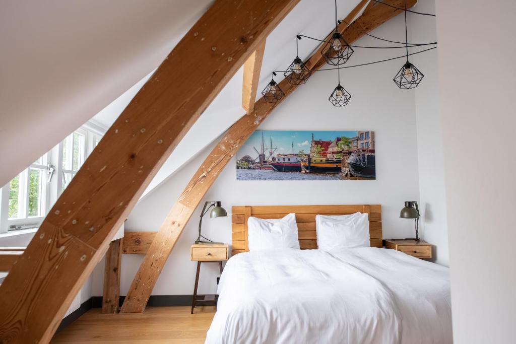 een slaapkamer met een wit bed en houten balken bij Boutique Hotel d'Oude Morsch in Leiden