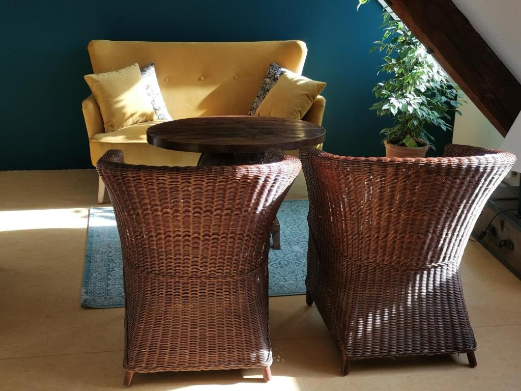 een tafel en twee rieten stoelen en een bank bij Dachstudio Herkulesblick in Kassel