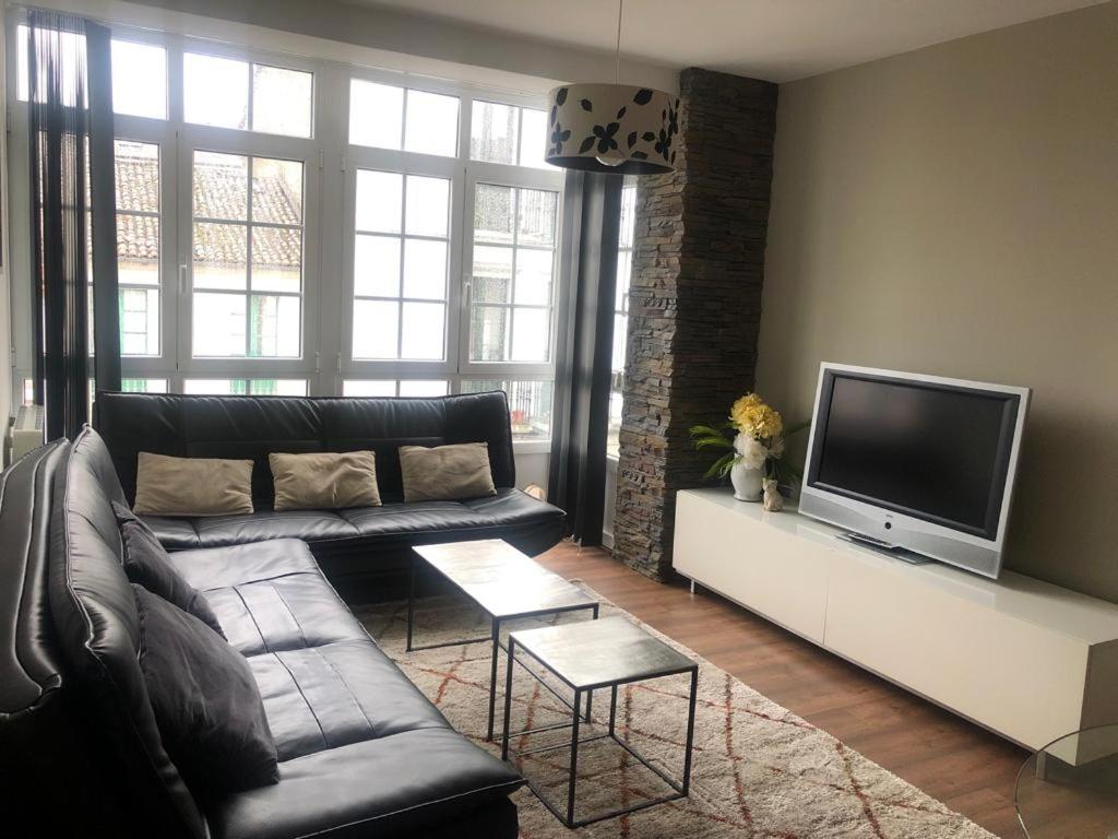 a living room with a couch and a flat screen tv at Apartamentos Castrón Douro in Santiago de Compostela