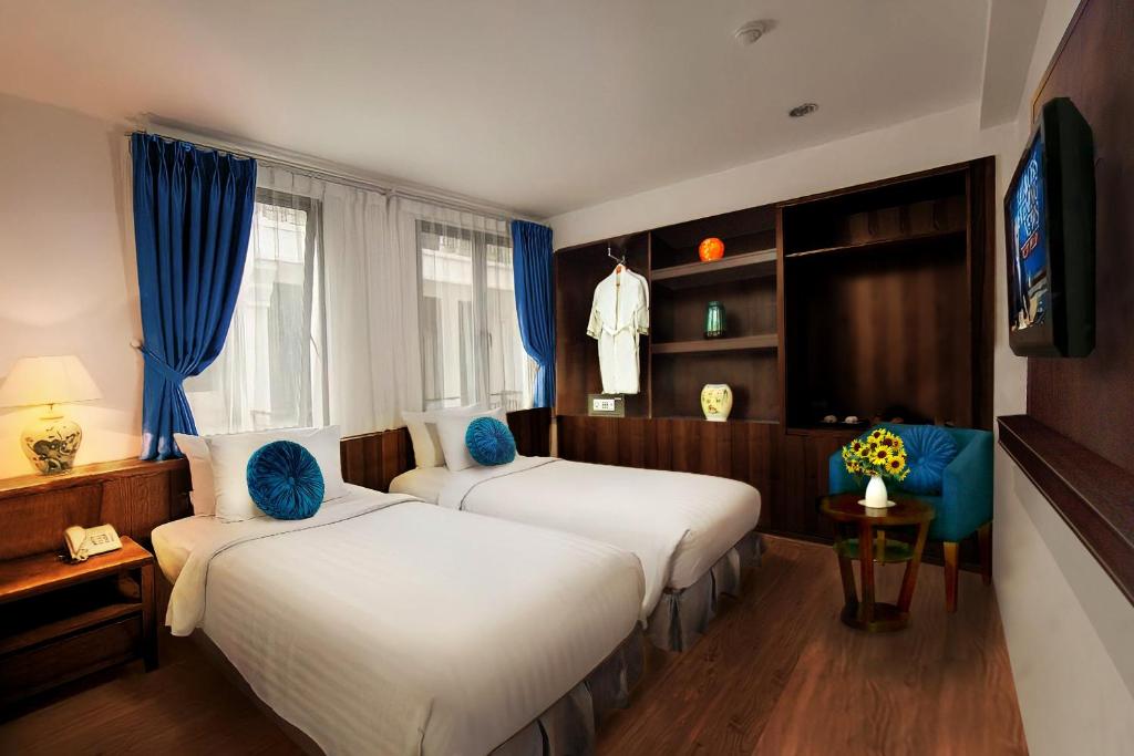 Cette chambre comprend deux lits et une télévision. dans l'établissement Aviary Hanoi Hotel & Travel, à Hanoï