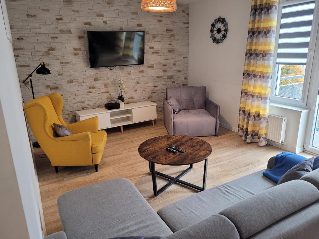 - un salon avec un canapé, des chaises et une télévision dans l'établissement Bm Apartamenty Przytulny apartament 142 w centrum Szczecina, à Szczecin