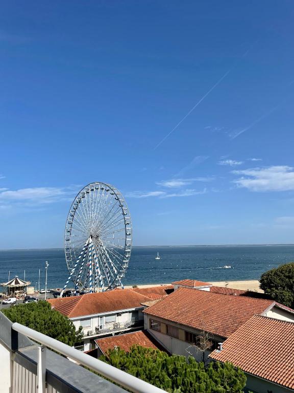 a ferris wheel in front of the ocean with buildings at Appart'hôtel Le Trianon in Arcachon