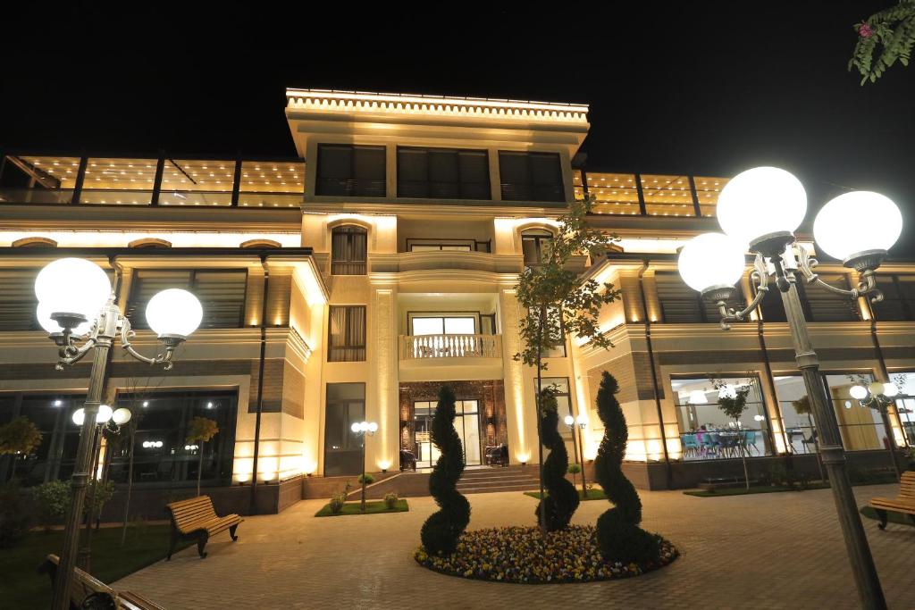 Un edificio con estatuas frente a él por la noche. en Turon Telecom Hotel, en G‘azalkent