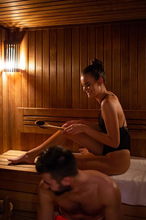 a woman sitting on a bed in a bath tub with a man at Amsterdam Hotel in Belgrade