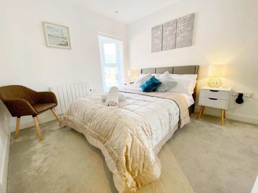 a white bedroom with a bed and a chair at Gild House 2-bedroom apartment close to Town Centre in Bournemouth