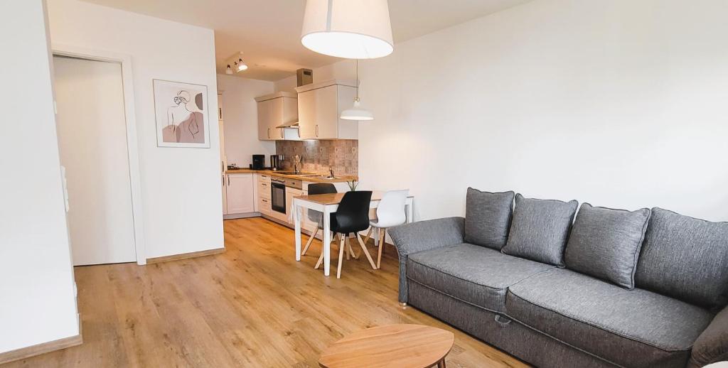 a living room with a gray couch and a kitchen at Wine & Hike in Wincheringen