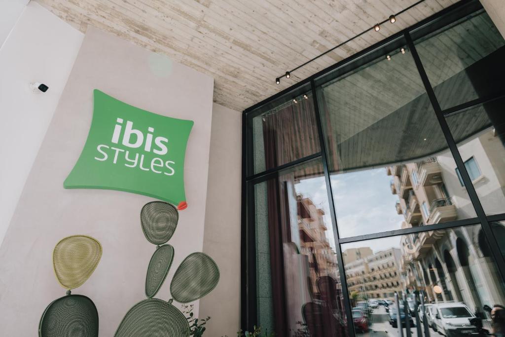 a sign on the side of a building with a business at ibis Styles ST Pauls Bay Malta in St Paul's Bay