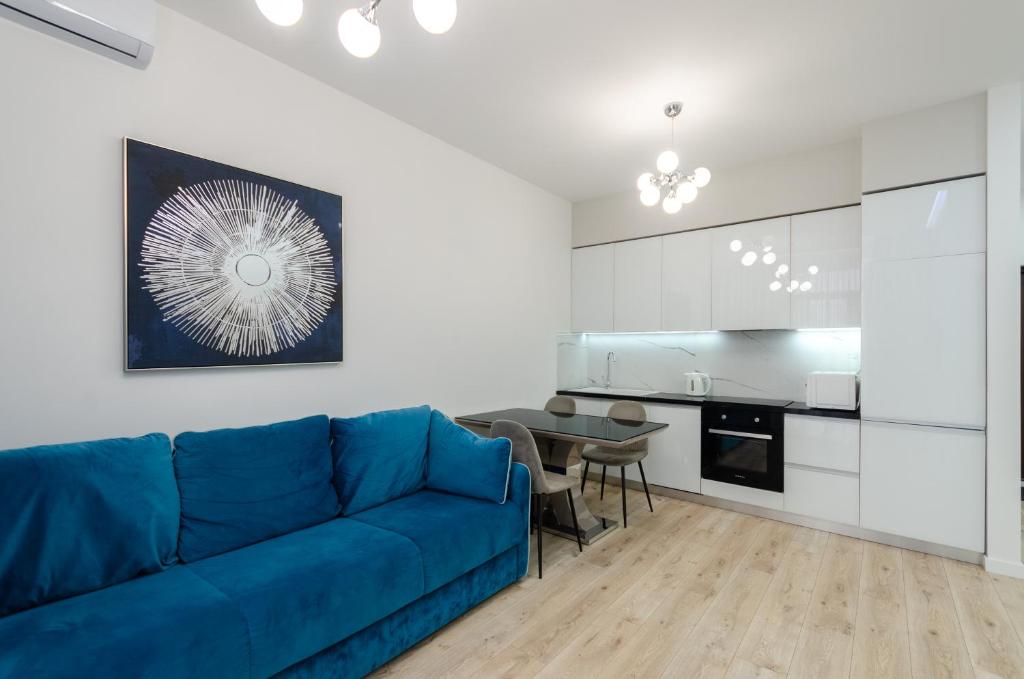 ein Wohnzimmer mit einem blauen Sofa und einer Küche in der Unterkunft 28485 Central park apartments in Kiew