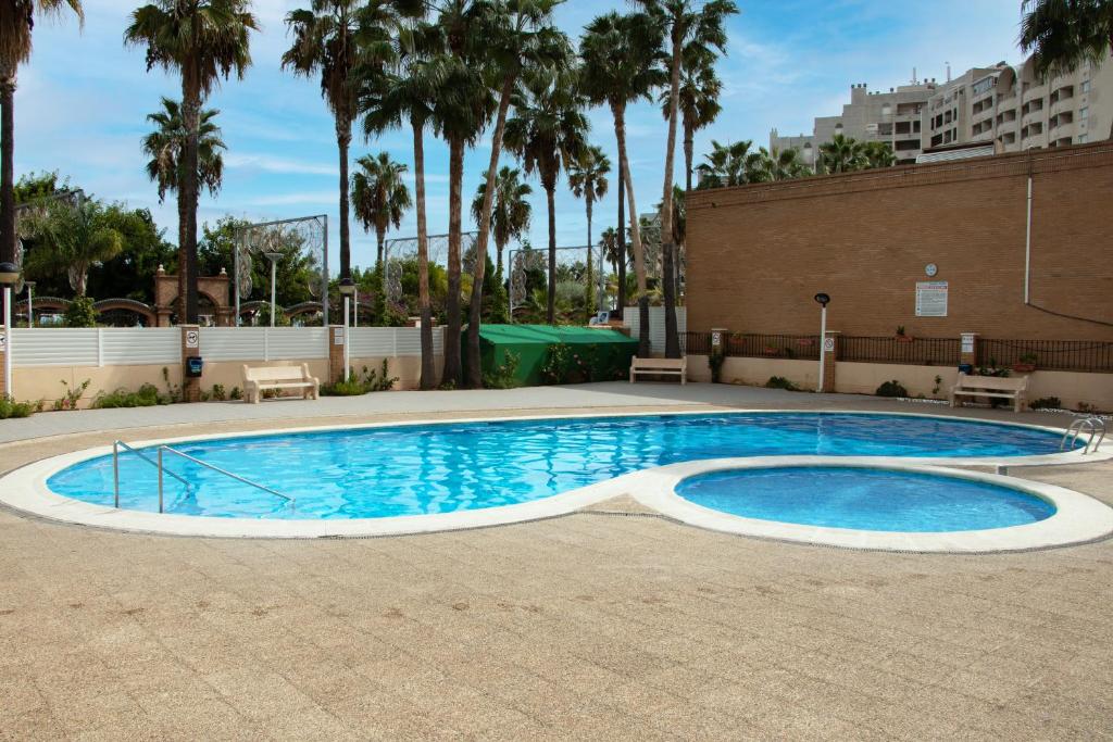 een zwembad op een binnenplaats met palmbomen bij Apartamento en 7ᵃ Planta - 1ᵃ Línea de Playa - Bahía Park, Marina d'Or in Oropesa del Mar