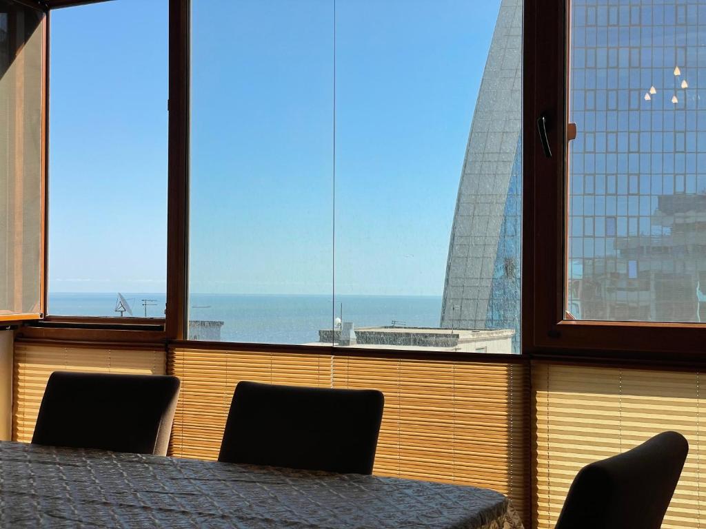 a table and chairs in a room with a view at Park Azure Sky apartment in Baku