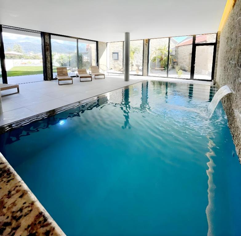 una piscina de agua azul en una casa en Lodges Minho, en Ponte da Barca