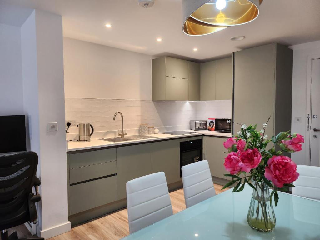 una cocina con un jarrón de flores sobre una mesa en Lovely Luxury Apartment with Free Parking 801, en Luton