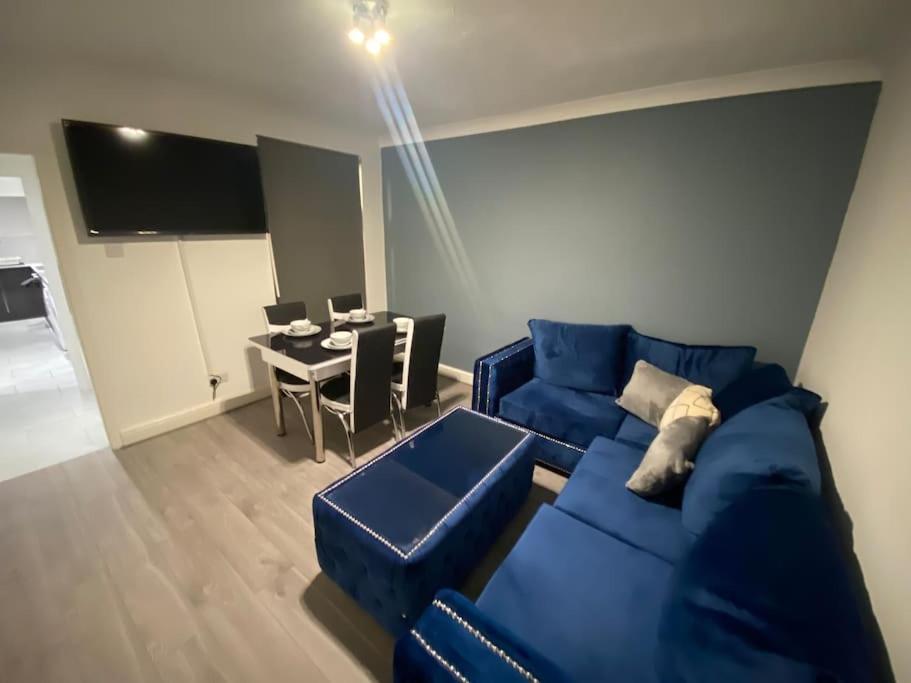 a living room with a blue couch and a table at MBA COSY 4 bedroom house in Leavesden Green