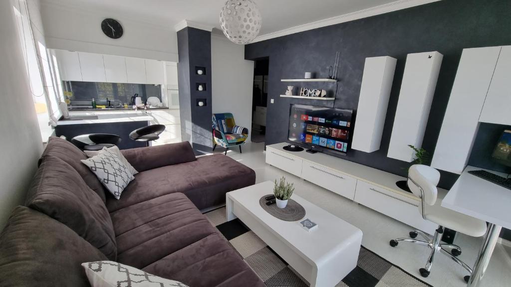 uma sala de estar com um sofá castanho e uma cozinha em Laura Exclusive, dizajnerski uređen stan, izvrsno opremljen em Vinkovci