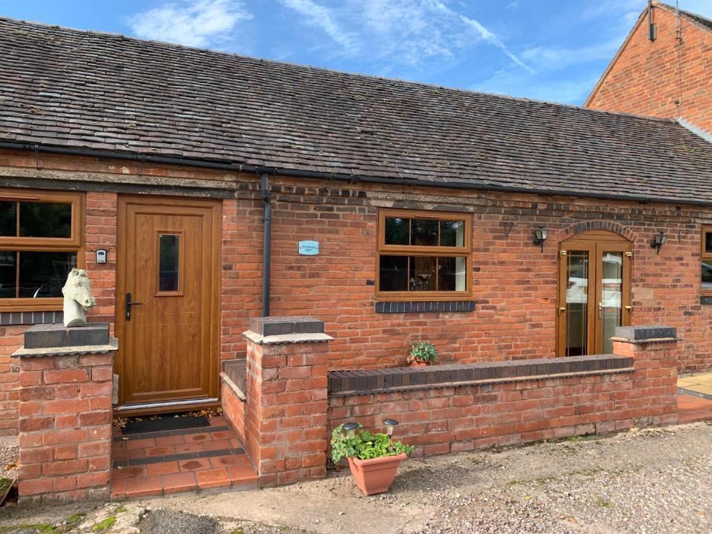 a brick house with a wooden door and windows at Brookside Barn in Lichfield