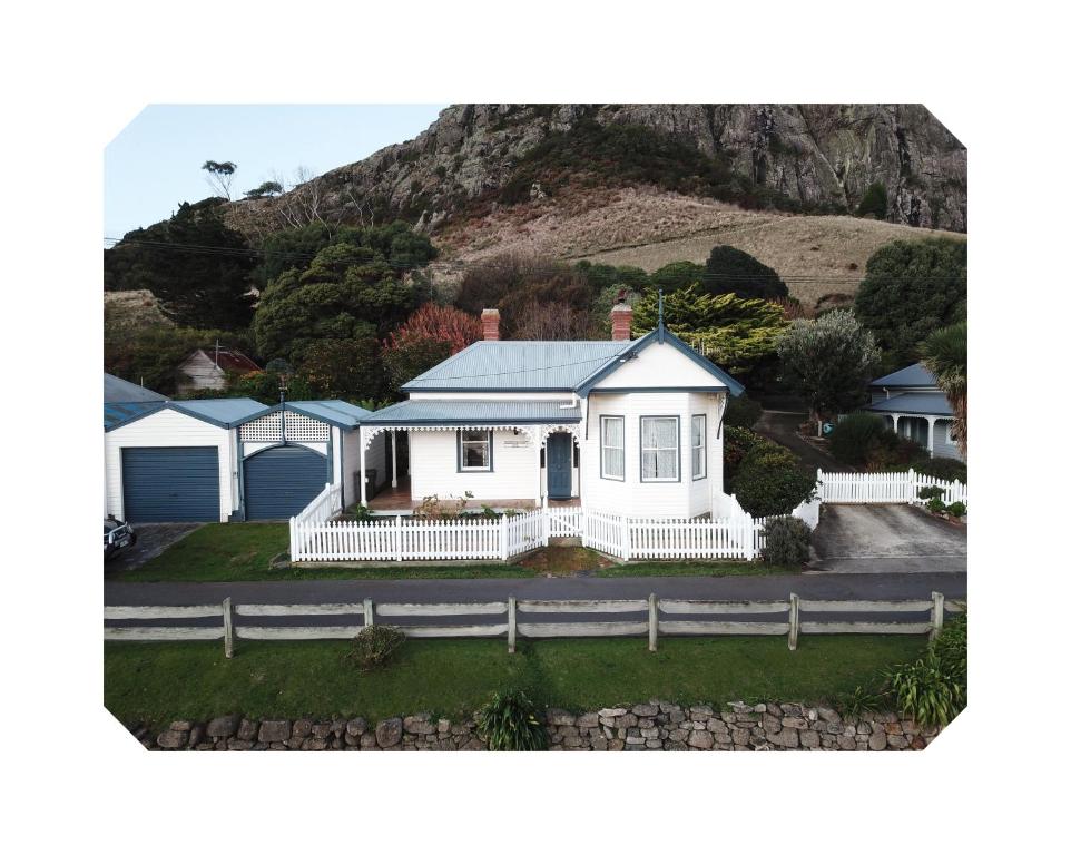 a white house with a mountain in the background at Harbour Master's Cottage in Stanley