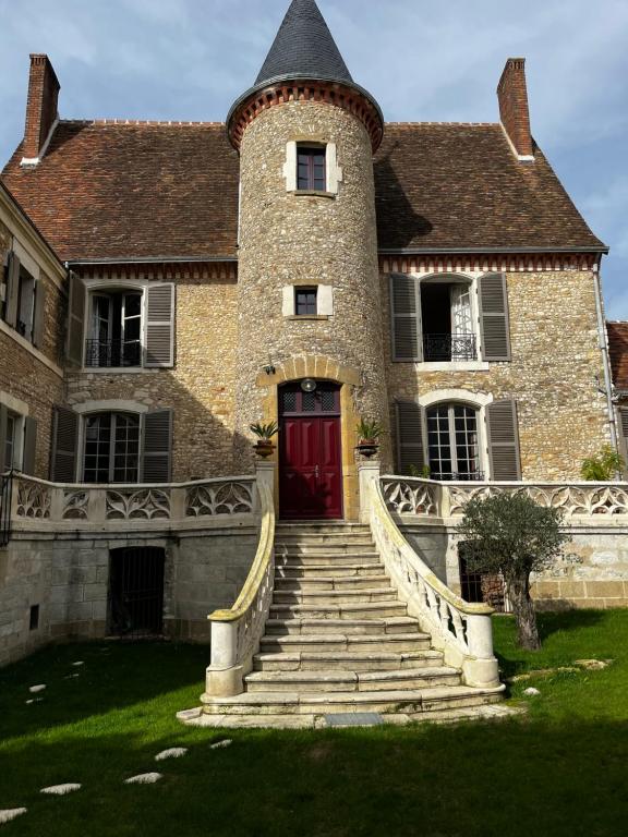 una gran casa de ladrillo con una puerta roja y escaleras en Chambres d'hôtes Place Balanant, en Buzançais
