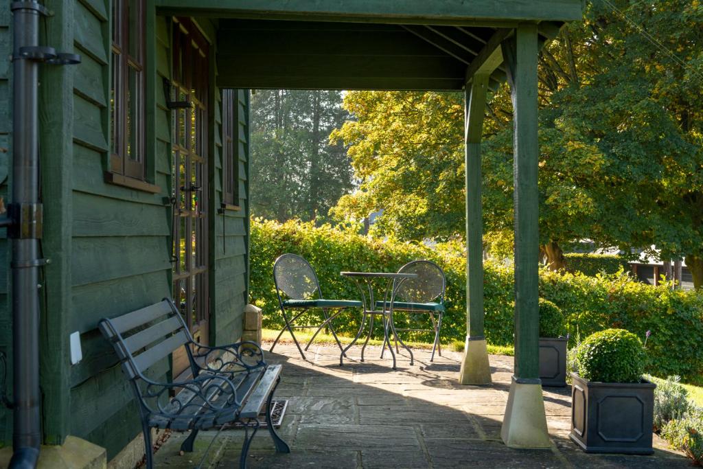 博克斯的住宿－Beautiful Cottage With Stunning Views in Box，凉亭的门廊配有椅子和桌子