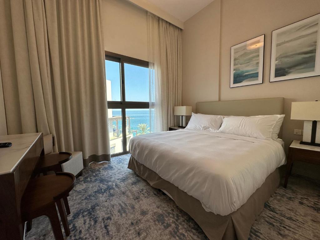 a hotel room with a bed and a large window at Address Beach Resort Residence Fujairah in Fujairah