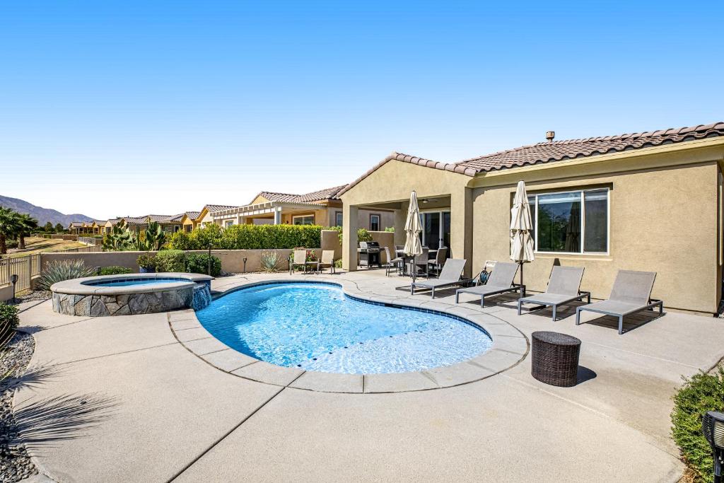 a patio with a pool and chairs and a house at Desert Princess Permit# BLIC-000,382-2022 in Cathedral City