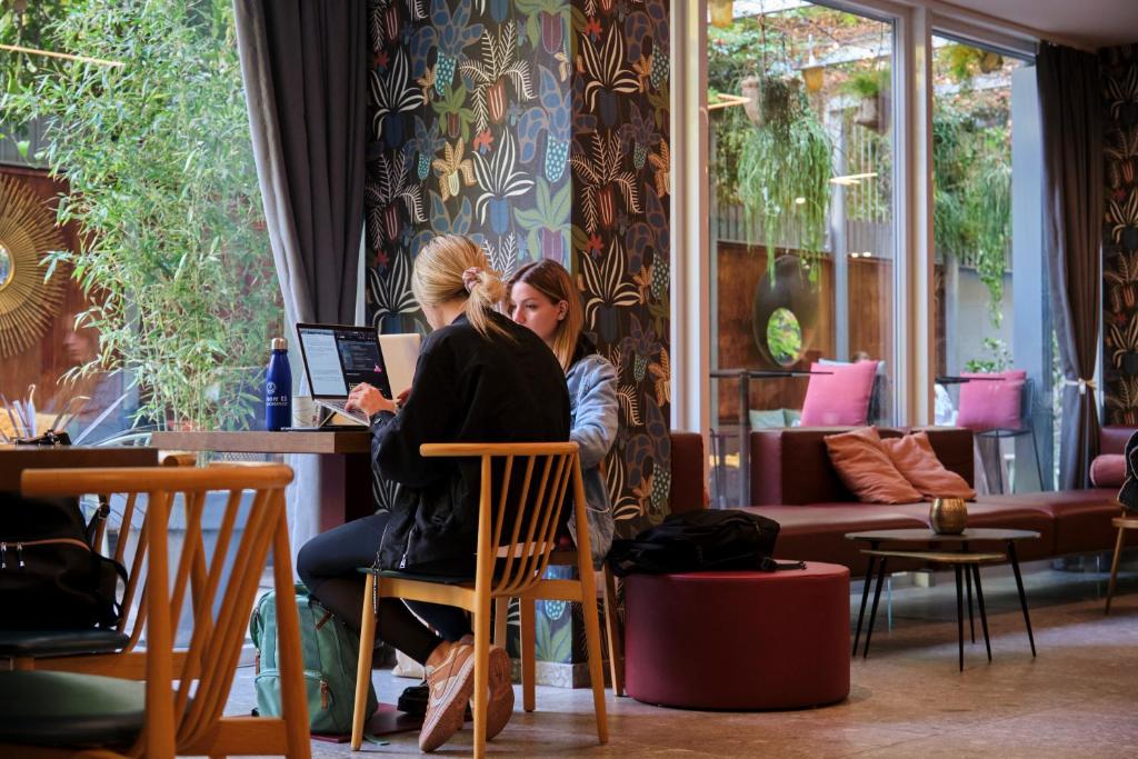 zwei Frauen an einem Tisch in einem Zimmer in der Unterkunft 21 House of Stories Città Studi in Mailand