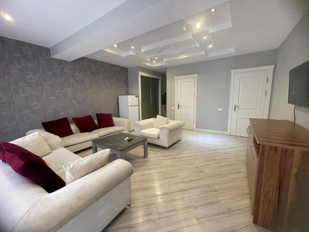 a living room with two white couches and a table at Luxe Azure Apartment in Baku