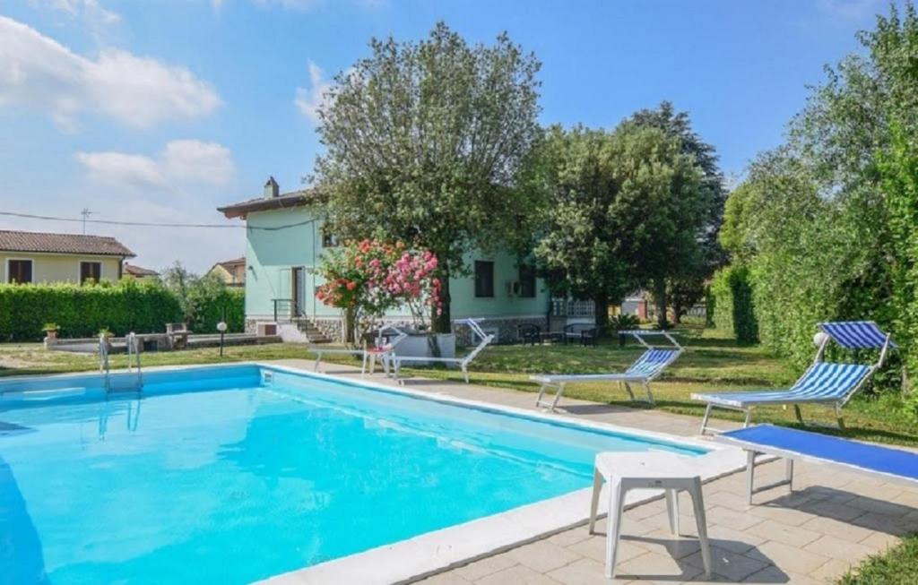una piscina con 2 sillas y una casa en Villino Franco by VacaVilla, en Orentano
