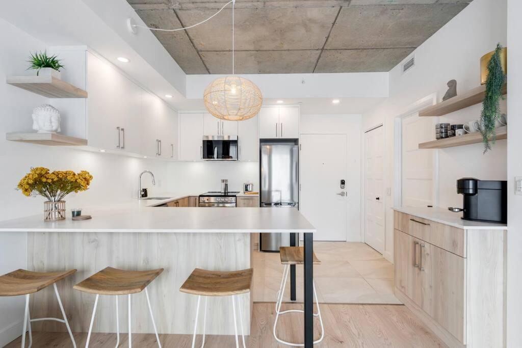 a kitchen with a large white counter and stools at Initial / Yogi+ Parking / Centre-Ville de Québec in Quebec City