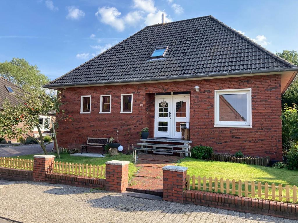 a small red brick house with a fence at Ferienwohnung Lopperland in Hinte in Hinte