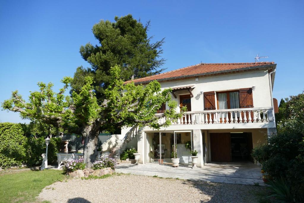 una gran casa blanca con un árbol en el patio en Appartement avec véranda donnant sur le jardin, en Le Pontet