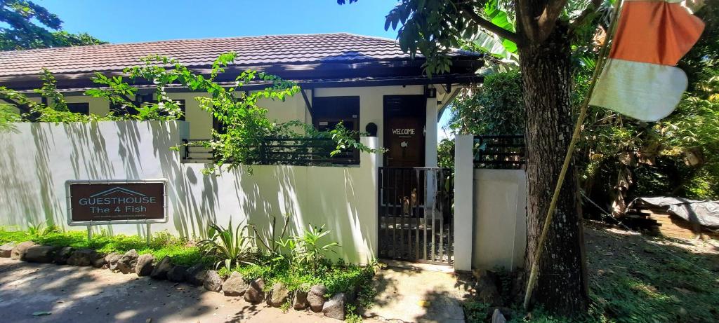 a small white house with a gate and a tree at Guesthouse The 4 Fish in Manado