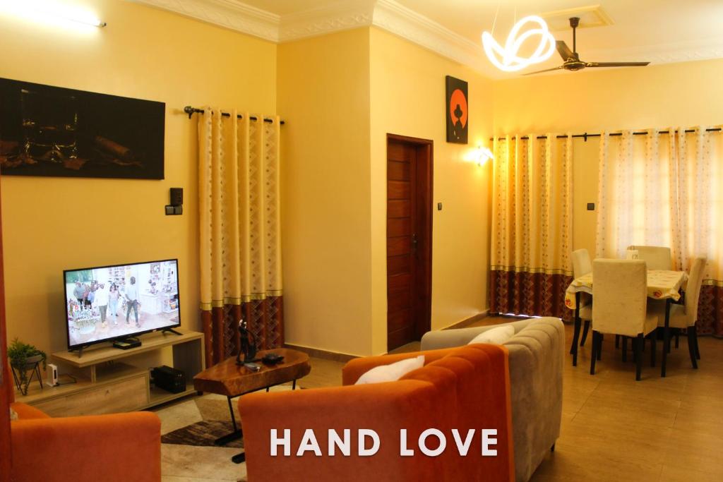 a living room with a television and a dining room at HAND LOVE in Cotonou