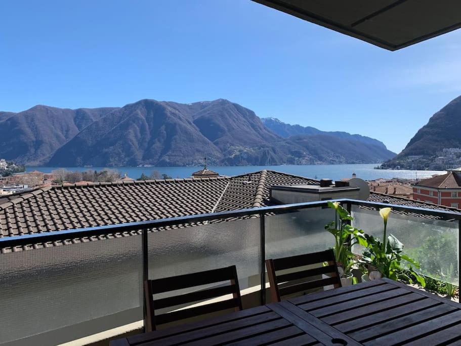 einen Balkon mit Blick auf das Wasser und die Berge in der Unterkunft SKY in Lugano