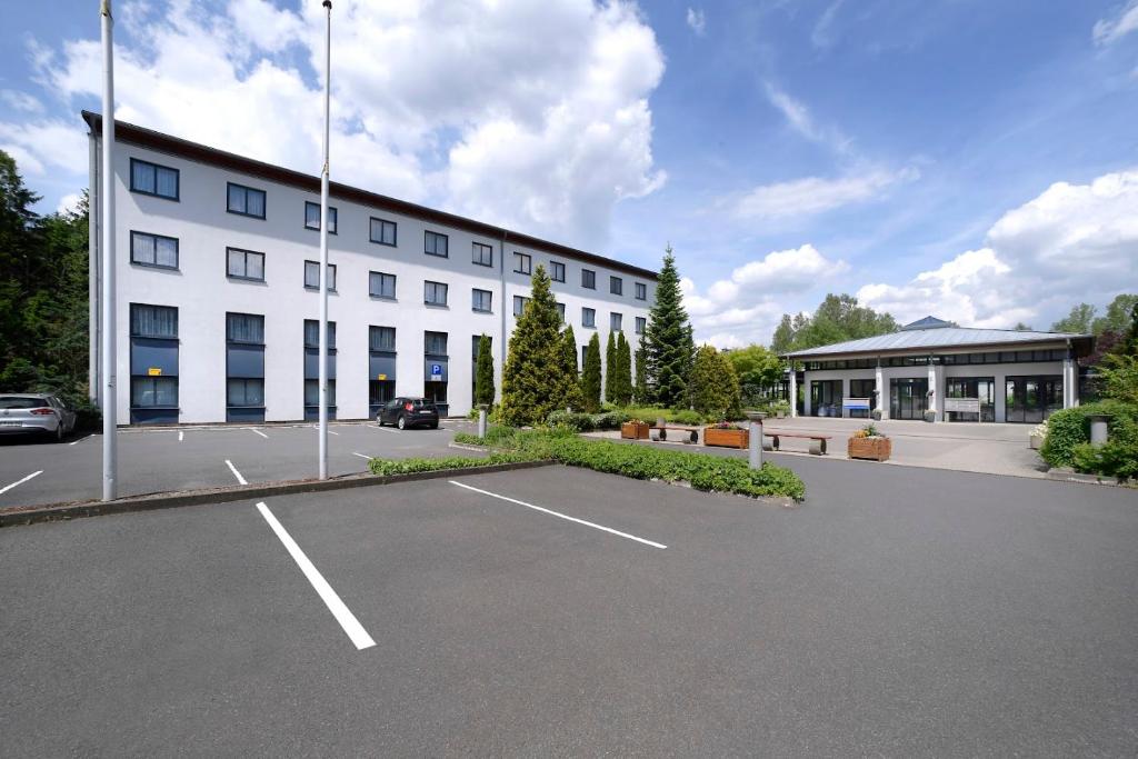 a large white building with a parking lot in front of it at Olympia Hotel Suhl in Suhl