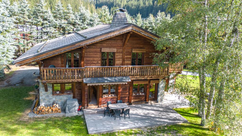 a log house with a deck and a table at Chalet Persévérance in Chamonix-Mont-Blanc