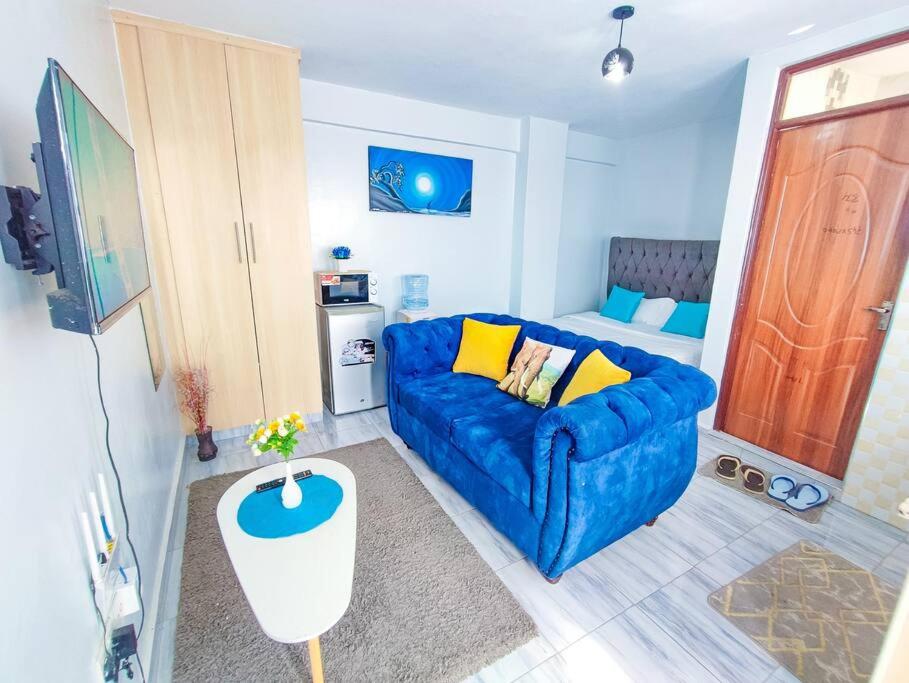 a living room with a blue couch in front of a door at LaMeg Furnished Studio in Fedha in Nairobi